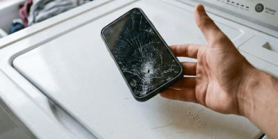 Smartphone with severely cracked screen placed on washing machine lid