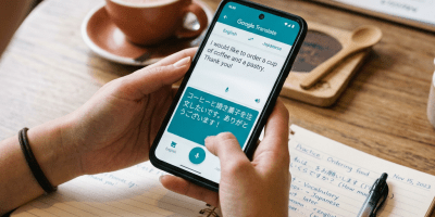 Hands holding smartphone with translation app and notebook